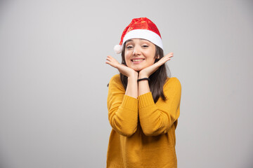 Beautiful woman in Santa hat feeling happy on gray background