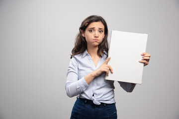 Naklejka premium Brunette painter holding canvas and sulking