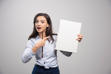 Brunette painter pointing at canvas on gray background