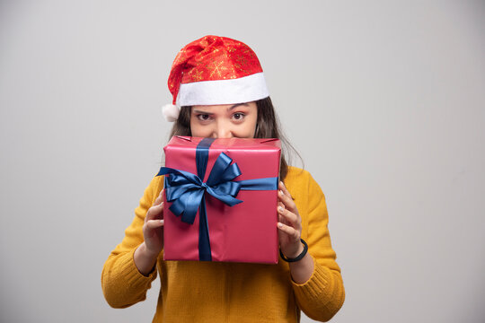 Happy woman in Santa hat hiding behind gift box