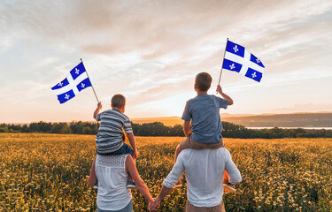 Naklejka premium Patriotic family waving Quebec flags on sunset