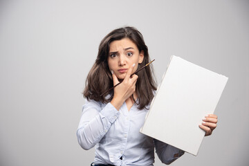 Naklejka premium Young girl holding empty canvas and thinking about something