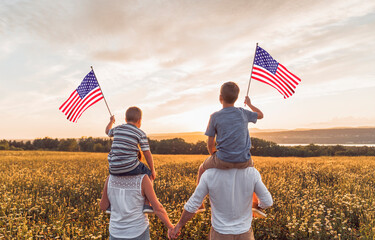 Patriotic family waving American USA flags on sunset