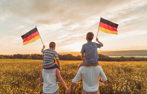 Patriotic family waving Germany flag on sunset