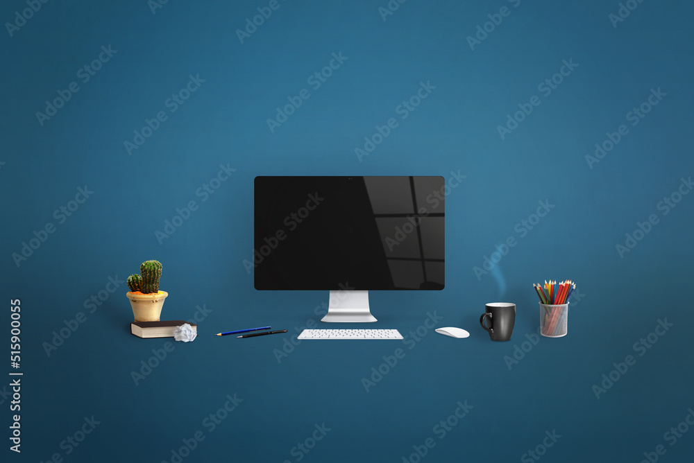 Poster computer display surrounded by office supplies on blue background. clean screen for web page promoti