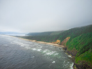 Beautiful summer landscape. Mountains on the ocean. Lots of greenery, forest. Light blue cloudless sky. Small waves crash on the sandy shore. The beauty of pristine nature, rest, relaxation.