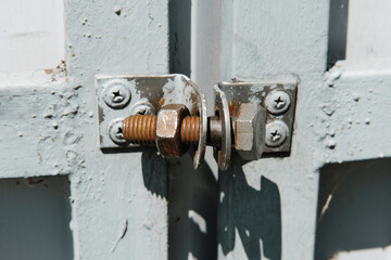 Old rusty bolt with screw nut used like a lock on the metal gate. Homemade lock.