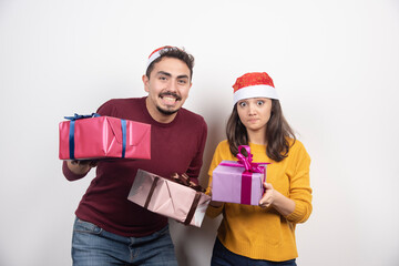 Happy couple with Christmas gifts over a white wall