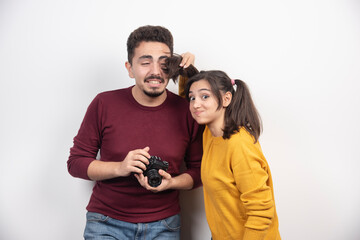 Cute couple taking pictures with camera and posing over a white wall