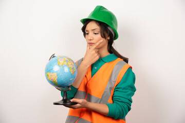 Female firefighter looking at globe with serious expression on white background