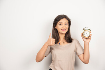 Young woman holding alarm clock on white background