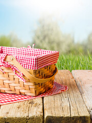 Against the background of summer nature, green grass, a picnic basket on a wooden table. Picnic,...