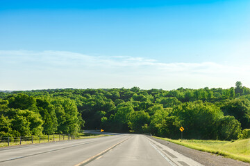 Scenic of greenery mountain, natural forest along with asphalt highway road with blue sky in spring and summer season. Long drive journey with green environment, road trip concept. Outdoor background.