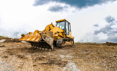 Track bulldozer, earth-moving equipment at construction site on dull day. Land clearing, grading, ground excavation of large job of new residential building. Construction heavy equipment for earthwork - obrazy, fototapety, plakaty