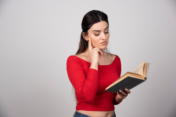 Photo of a serious woman reading a book and holding a pencil