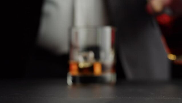 Drinking brandy or whiskey close-up. Rich man drinks luxury cognac. Barkeeper giving alcohol amber rum, liqour beverage in glass.