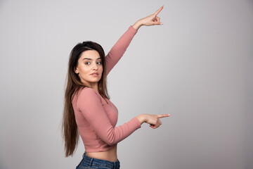 Image of beautiful young woman standing and pointing up
