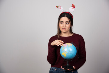 Young woman in Christmas headband holding an Earth globe