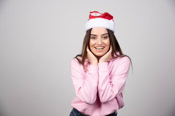 Smiling woman in Santa Claus red hat correcting hair