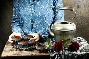 closeup woman holding homemade chocolate nuts muffins decorated with candied cherry
