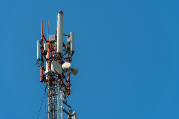 New GSM antennas on a high tower against a blue sky for transmitting a 5g signal are dangerous to...