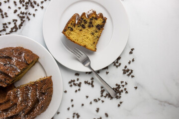 An ornate and decorative homemade and fresh chocolate chip bundt cake with a clice cut out on top of a serving plate