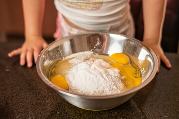 Imagem de mãe e filha brincando enquanto cozinham um bolo. Mulher loira brincando com sua filha na cozinha. Receita de doce feita em família.
