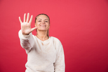 Young woman smiling and showing number five with fingers.