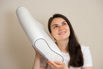 A woman holds an orthopedic pillow made of memory foam and smiles. Choosing the right pillow for...