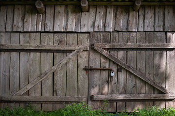Naklejka premium Old gate made of weathered boards in a rustic barn. Retro background in eco style.