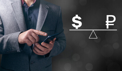 On the scales the ruble and the dollar. Man holding a phone in his hand