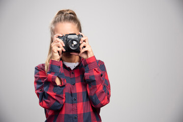 Blonde photograph in checked shirt takes photos as a professional
