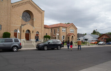 Hispanic and Caucasian People Enter a Catholic Church on Cloudy Sunday Morning