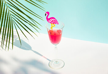 Creative summer composition with glass of juice, flamingo and palm leaf. Minimal summer drink...