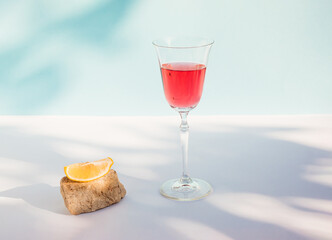 Creative summer composition with fresh red beverage, lemon slice, stone and shadow. Minimal summer drink concept.