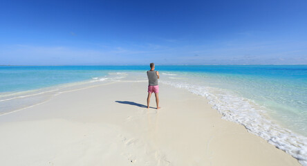 one man on a tropical island with white sand in the ocean