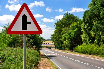 UK road sign. Side Road Ahead along a country lane. Blue cloudy sky © NottmCity