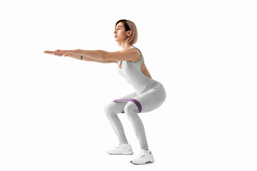 Fototapeta premium Sexy woman in sportswear using a resistance band in her exercise routine. Young woman performs fitness exercises on white background. Isolate