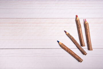 MESA DE MADERA BLANCA CON CUATRO LAPICES GRANDES DE MADERA RUSTICA.