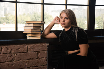 Young woman posing with books near of window