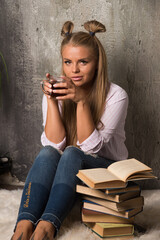 Woman sitting on floor with tea and book on marble background