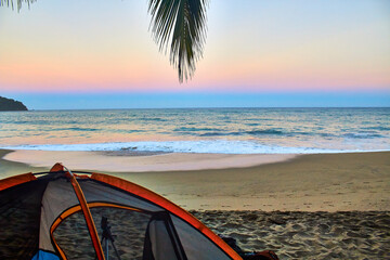 camping tent in front of the beach at sunrise with beautiful colors sand and plam tree in first plane on sayulita beach 