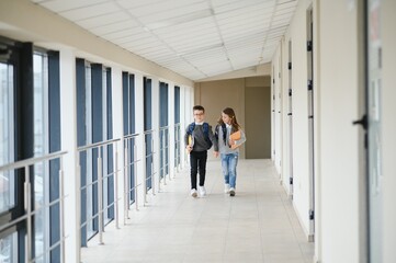 Portrait of smiling school kids in school corridor with books