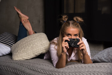 Woman lying on bed with camera on dark background