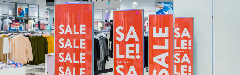 Sale sign at the entrance to clothing store,large red panels with white words. Seasonal discount...