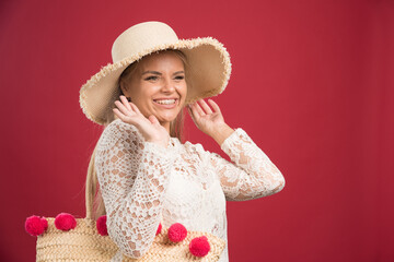 Smiling woman with hat and bag on red background