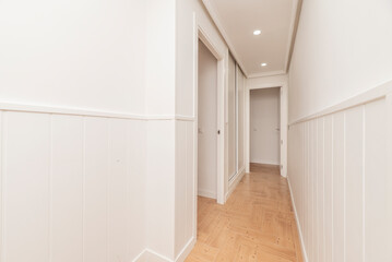 Corridor of a house with several doors and access to different rooms, all in white and wood-like ceramic stoneware floors