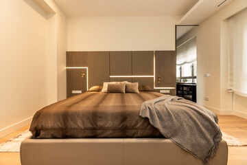 Bedroom with large designer double bed in brown upholstered leather with matching bedding