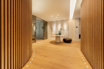 Hallway of a house with walls covered with latticework of vertical wooden slats, lamps on the light...