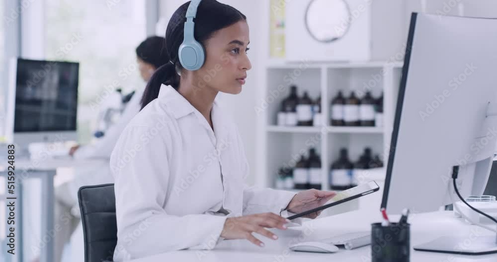 Poster scientist using computer, digital tablet, listening to music on headphones and working in laboratory